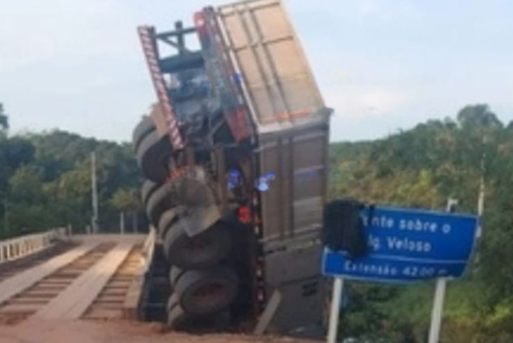 ACIDENTE: Carreta tomba e fica pendurada em ponte de madeira na BR-319